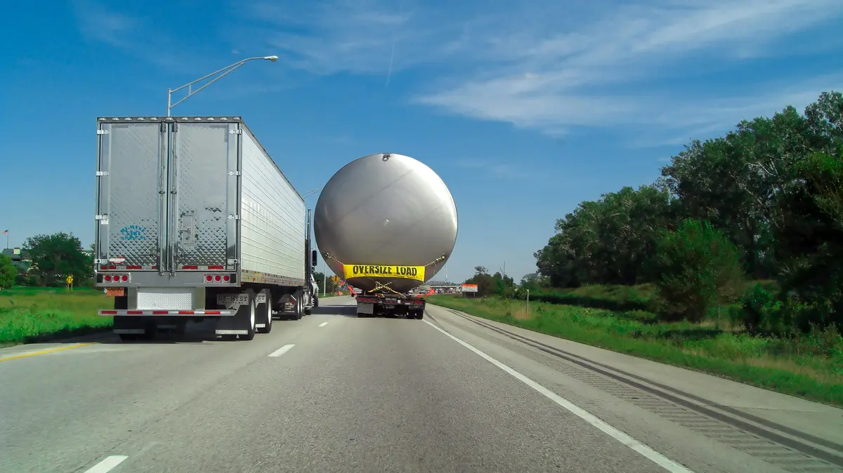 Tractocamión trasladando un tanque esférico de sobredimensión por carretera